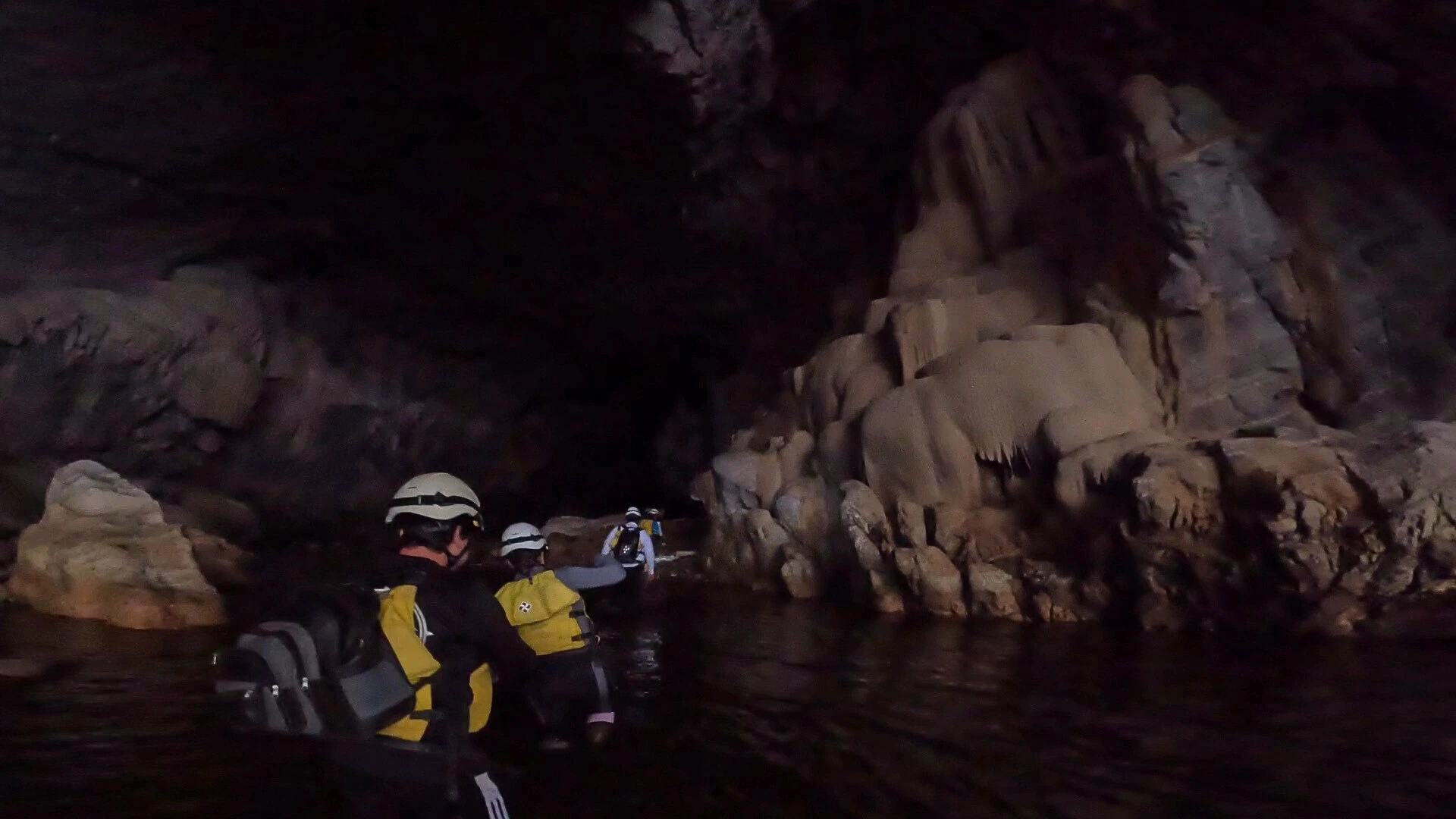 Exploración en cueva con agua clara y casco
